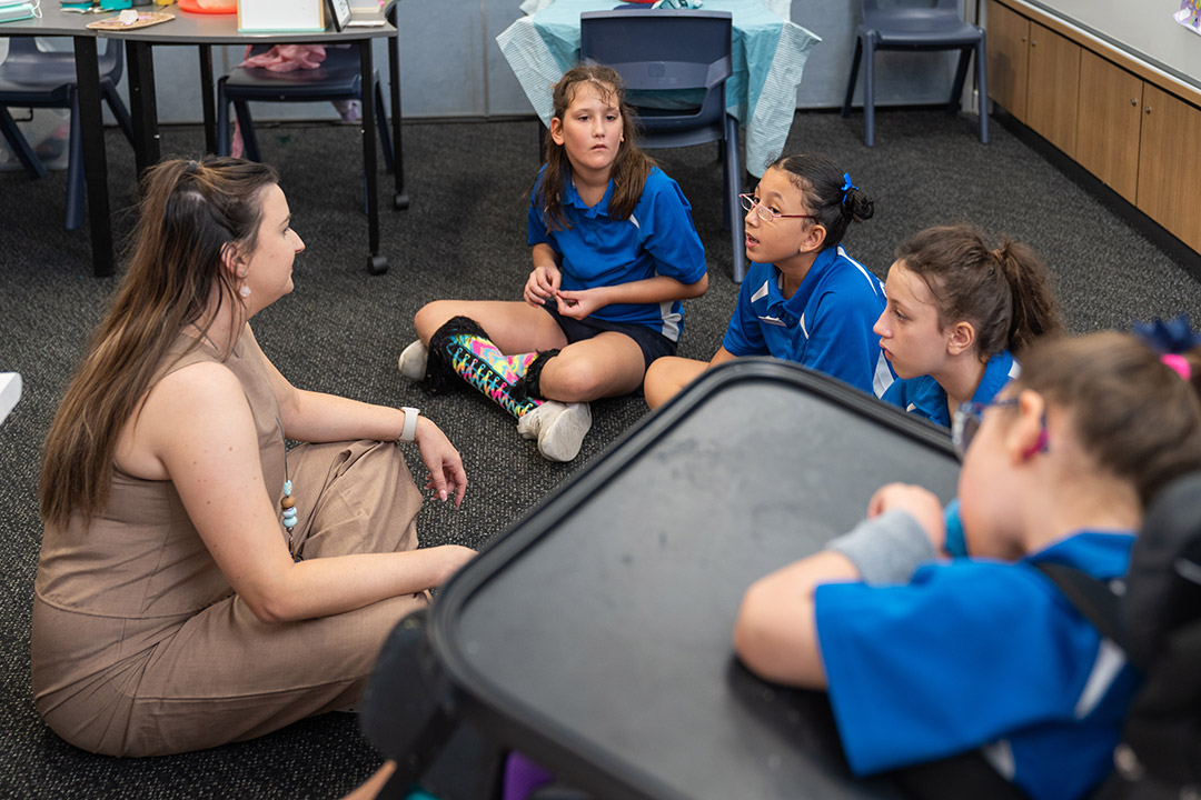 A teacher and a small group of primary school students sat in a circle having a conversation.