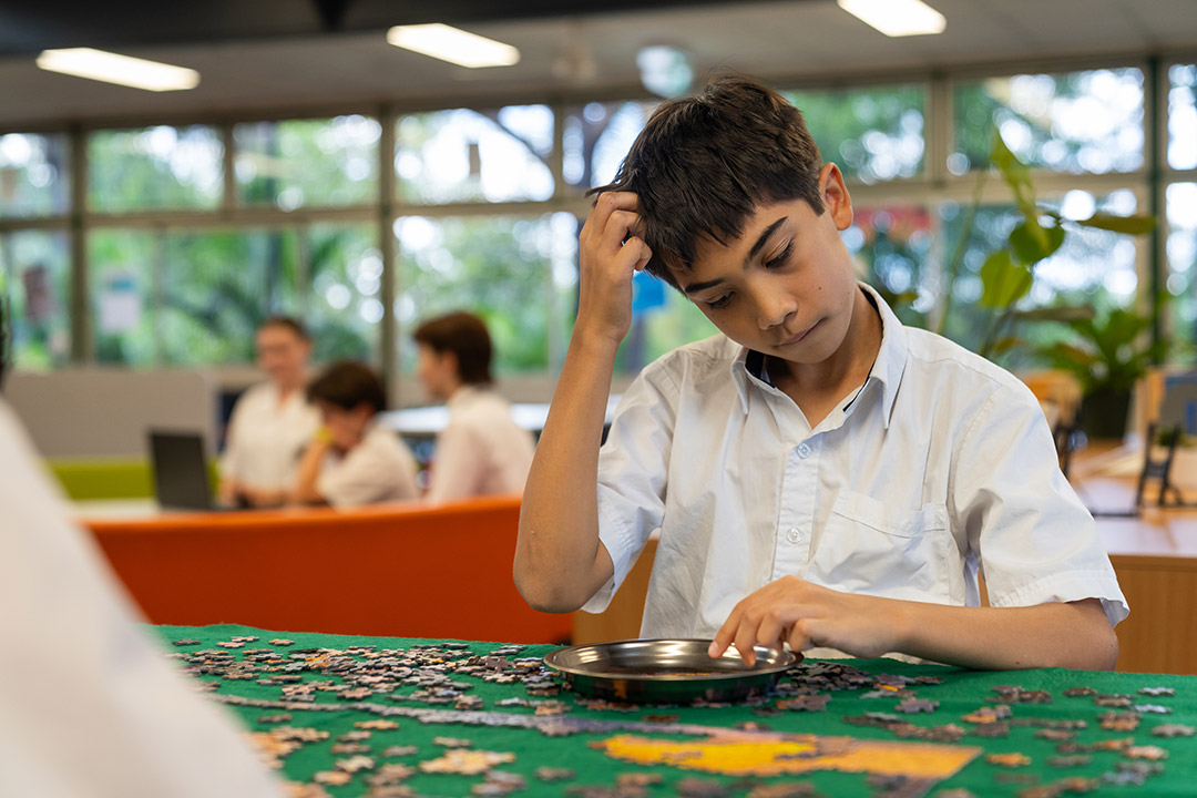 A student completing a puzzle and scratching his head, as if thinking