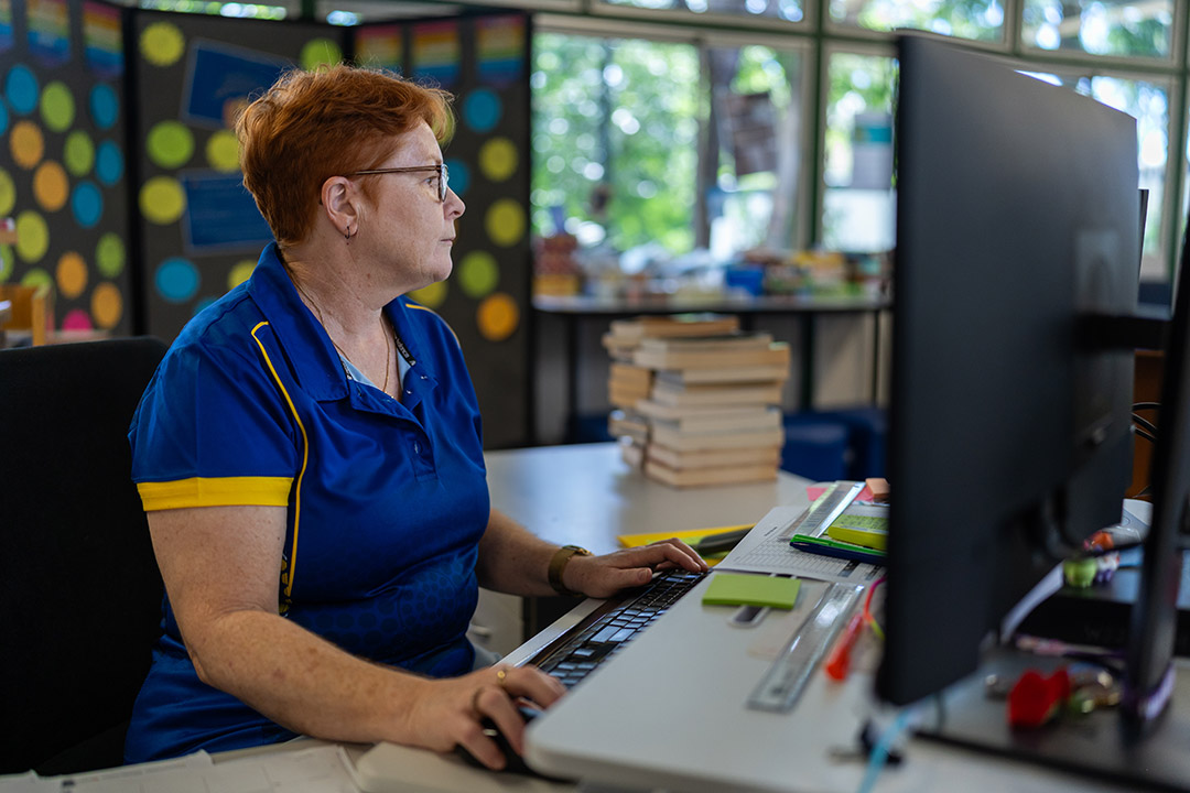 Teacher sitting at desktop computer